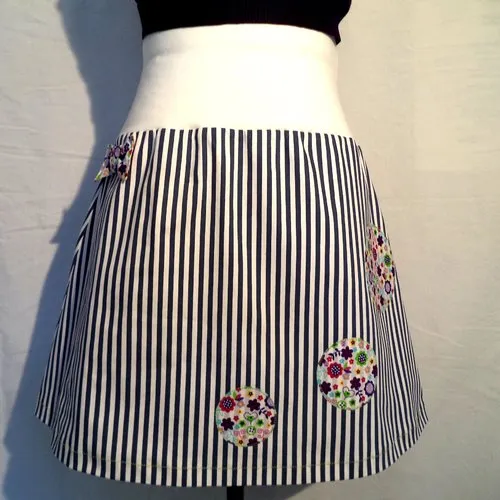 Jupe trapèze à rayures marine et blanc , ceinture large, unie et extensible. noeud et appliqués contrastants sur le devant, fait