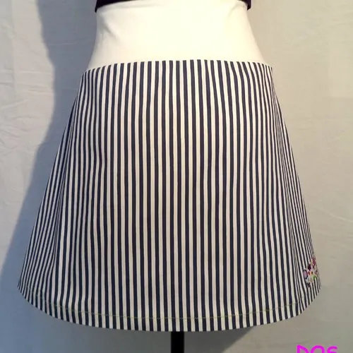 Jupe trapèze à rayures marine et blanc , ceinture large, unie et extensible. noeud et appliqués contrastants sur le devant, fait